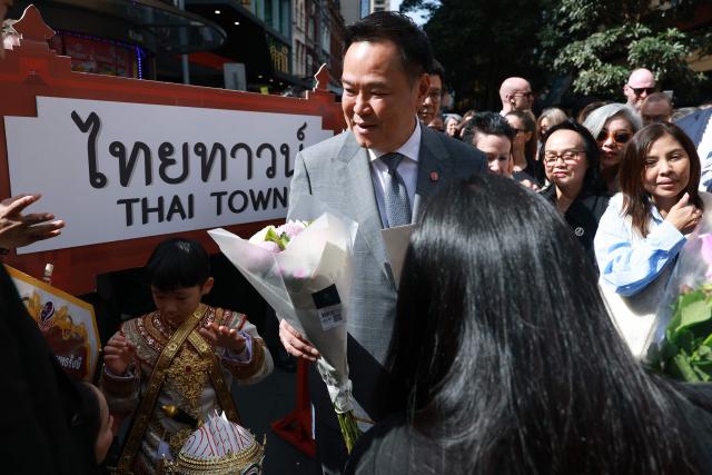 Thailand's Prime Minister Anutin Charnvirakul (C) reacts as he receives flowers during a visit to Thaitown in Sydney on August 18, 2026. The Thai Prime Minister is on a three-day official visit to Australia. (Photo by DAVID GRAY / AFP)