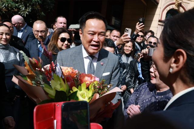 Thailand's Prime Minister Anutin Charnvirakul (C) reacts as he receives flowers during a visit to Thaitown in Sydney on August 18, 2026. The Thai Prime Minister is on a three-day official visit to Australia. (Photo by DAVID GRAY / AFP)