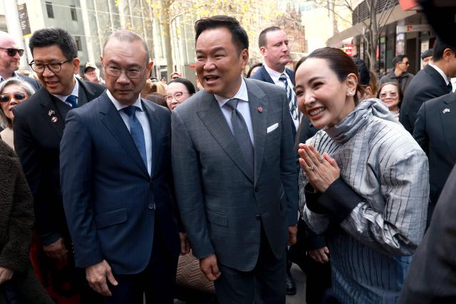Thailand's Prime Minister Anutin Charnvirakul (C) and his wife Thananon Niramit (R) react to members of the public as they visit Thaitown in Sydney on August 18, 2026. The Thai Prime Minister is on a three-day official visit to Australia. (Photo by DAVID GRAY / AFP)