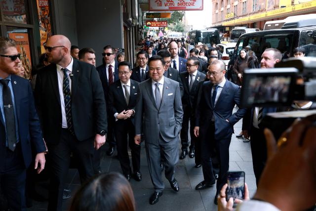 Thailand's Prime Minister Anutin Charnvirakul (C) reacts as he walks with officials during a visit to Thaitown in Sydney on August 18, 2026. The Thai Prime Minister is on a three-day official visit to Australia. (Photo by DAVID GRAY / AFP)