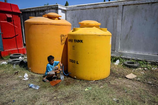 A child fills potable water from a tank in Maumere, East Nusa Tenggara, on August 18, 2026, following a 7.7-magnitude earthquake that struck Indonesia's Flores island on August 15. Thousands of people displaced by a powerful earthquake in eastern Indonesia awaited much-needed aid on August 17 as they camped out at schools, police stations and government offices, with many stuck outside. (Photo by JUNI KRISWANTO / AFP)