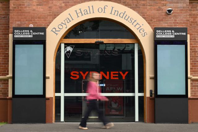 A girl walks past the Sydney Swans' headquarters building in Sydney on August 18, 2026. Top Australian Rules side the Sydney Swans said it was "extremely shocked and disappointed" on August 17 after several unidentified players were involved in an "alleged incident" in Melbourne. (Photo by Saeed KHAN / AFP)