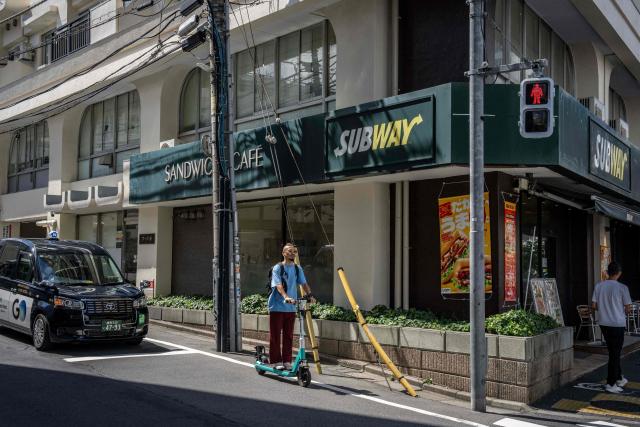 A man rides an electric scooter along a road in Tokyo on August 18, 2026. (Photo by Yuichi YAMAZAKI / AFP)