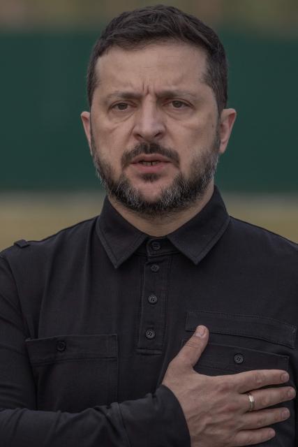 Ukraine's President Volodymyr Zelensky stands at attention as he attends the reburial ceremony of the repatriated remains of Yevhen Konovalets, leader of the Organisation of Ukrainian Nationalists (OUN), who was killed by a Soviet agent in 1938, at the National Military Memorial Cemetery near Kyiv on August 18, 2026, amid the Russian invasion of Ukraine. (Photo by Roman PILIPEY / AFP)