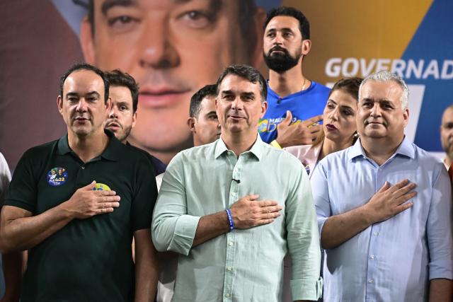 Senator and right-wing presidential candidate Flavio Bolsonaro (C), his running mate, Alfredo Gaspar (R), and the candidate for governor of Minas Gerais, Flavio Roscoe, attend a rally at Mackenzie Esporte Clube in Belo Horizonte, Brazil on August 17, 2026. Brazilians will go to the polls next October 4 once again deeply polarized and under the shadow of US President Donald Trump, who has backed conservative candidates in recent elections in Latin America. (Photo by Gledston Tavares / AFP)