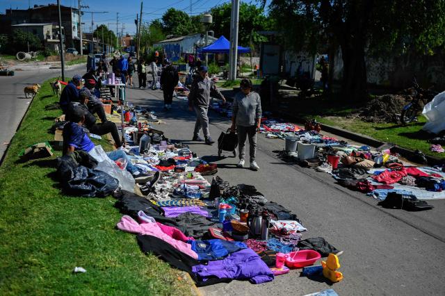(FILES) People walk through a street market in Villa Fiorito, on the outskirts of Buenos Aires, on October 19, 2025. Household arrears in Argentina have tripled in twelve months and reached in 2026 their highest level in 20 years during Javier Milei’s government. The main problem is stagnant incomes and soaring living costs, particularly due to utility bills, which have far outstripped inflation since the ultra-liberal president came to power in December 2023. (Photo by Luis ROBAYO / AFP)