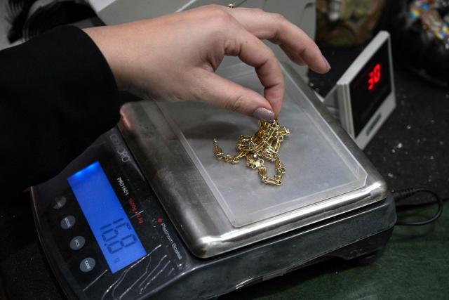 (FILES) An appraiser weights gold jewelry at a gold dealership in Buenos Aires on June 6, 2024. Household arrears in Argentina have tripled in twelve months and reached in 2026 their highest level in 20 years during Javier Milei’s government. The main problem is stagnant incomes and soaring living costs, particularly due to utility bills, which have far outstripped inflation since the ultra-liberal president came to power in December 2023. (Photo by JUAN MABROMATA / AFP)