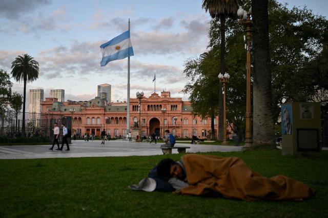(FILES) A homeless man sleeps at Plaza de Mayo square in front of Casa Rosada presidential palace in Buenos Aires on September 25, 2024. Household arrears in Argentina have tripled in twelve months and reached in 2026 their highest level in 20 years during Javier Milei’s government. The main problem is stagnant incomes and soaring living costs, particularly due to utility bills, which have far outstripped inflation since the ultra-liberal president came to power in December 2023. (Photo by LUIS ROBAYO / AFP)