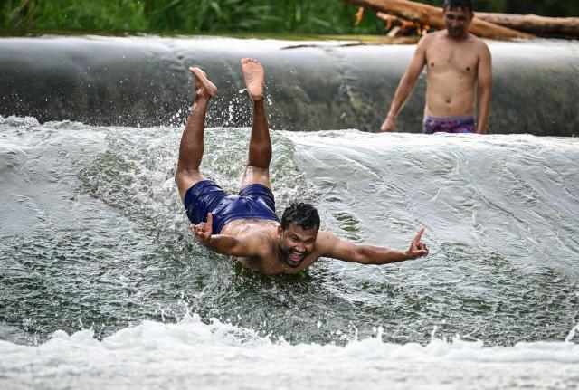 Asian workers enjoy cooling off from the summer heat in the water of Ciorogarla river, near Bucharest, Romania, on August 18, 2026. Romania has seen a significant influx of South Asian and Southeast Asian laborers in recent years to fill critical labor shortages in the construction and infrastructure sectors. (Photo by Daniel MIHAILESCU / AFP)