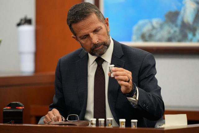 Dean O'Kelley, a Las Vegas police officer who attended the scene of shooting, holds shell casings as he testifies during the murder trial of Duane Davis, related to the 1996 killing of rapper Tupac Shakur, at the Clark County District Court at the Regional Justice Center in Las Vegas, Nevada, on August 18, 2026. The trial of the former gang leader accused of orchestrating the murder of rapper Tupac Shakur began on August 10, 30 years after one of America's most high-profile unresolved killings. The proceedings, expected to last a month, will likely not make clear who fired the shots that killed the California hip-hop legend on the night of September 7, 1996, while he was in Las Vegas to see a Mike Tyson boxing match. (Photo by John Locher / POOL / AFP)