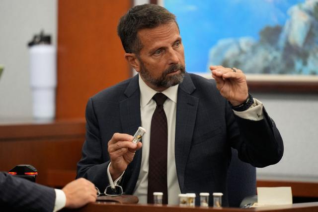 Dean O'Kelley, a Las Vegas police officer who attended the scene of shooting, holds shell casings as he testifies during the murder trial of Duane Davis, related to the 1996 killing of rapper Tupac Shakur, at the Clark County District Court at the Regional Justice Center in Las Vegas, Nevada, on August 18, 2026. The trial of the former gang leader accused of orchestrating the murder of rapper Tupac Shakur began on August 10, 30 years after one of America's most high-profile unresolved killings. The proceedings, expected to last a month, will likely not make clear who fired the shots that killed the California hip-hop legend on the night of September 7, 1996, while he was in Las Vegas to see a Mike Tyson boxing match. (Photo by John Locher / POOL / AFP)