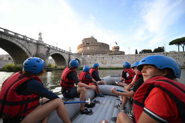 People raft in a rubber dinghy on the Tiber River, past Castel Sant'Angelo, on a stretch of the river that runs entirely within the urban area of central Rome, on August 14, 2026. Rafting on the Tiber offers relief from Rome heatwave on a rafting route on the Tiber taking place entirely within the urban area and taking approximately two hours. (Photo by Andreas SOLARO / AFP)