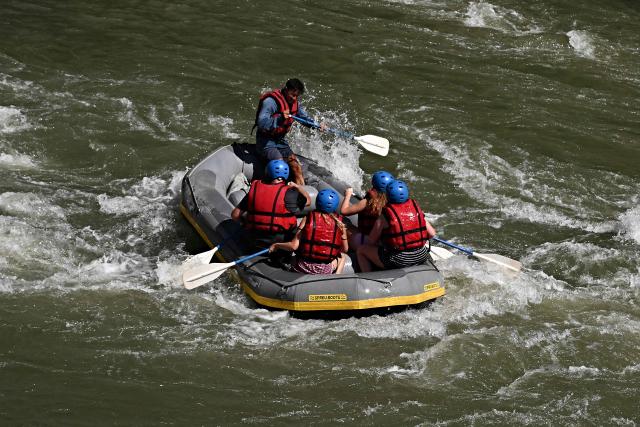 People raft in a rubber dinghy on the Tiber River, which runs entirely within the urban area of central Rome, on August 14, 2026. Rafting on the Tiber offers relief from Rome heatwave on a rafting route on the Tiber taking place entirely within the urban area and taking approximately two hours. (Photo by Andreas SOLARO / AFP)