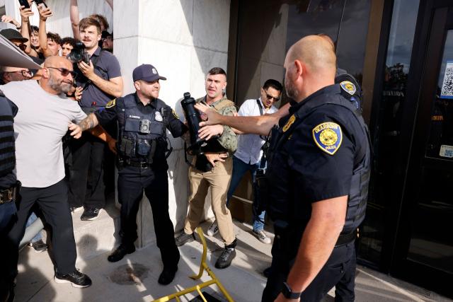 Police gesture near far-right US activist Jake Lang (C) during an anti-Muslim demonstration he organized called the "Christian Crusade March" in Dearborn, Michigan, on August 18, 2026. (Photo by JEFF KOWALSKY / AFP)