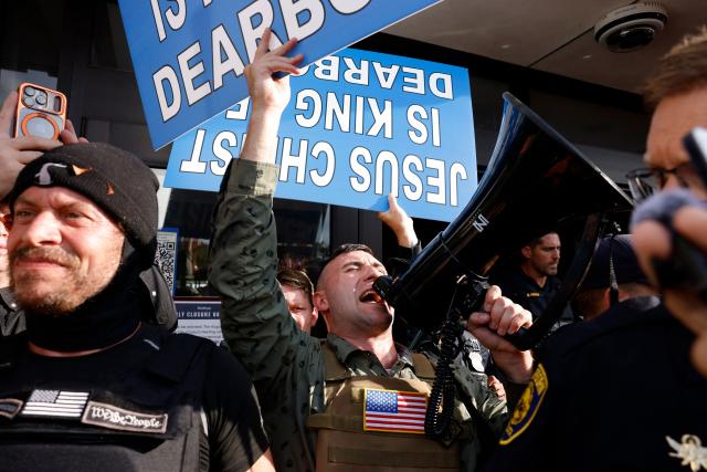 Far-right US activist Jake Lang (C) holds up a sign during an anti-Muslim demonstration he organized called the "Christian Crusade March" in Dearborn, Michigan, on August 18, 2026. (Photo by JEFF KOWALSKY / AFP)