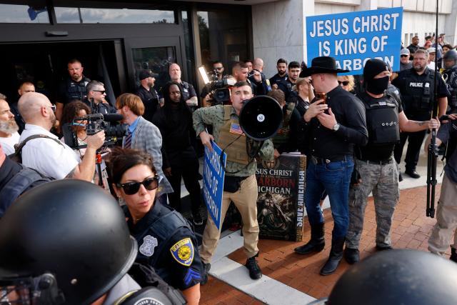 Far-right US activist Jake Lang (C) speaks into a megaphone during an anti-Muslim demonstration he organized called the "Christian Crusade March" in Dearborn, Michigan, on August 18, 2026. (Photo by JEFF KOWALSKY / AFP)