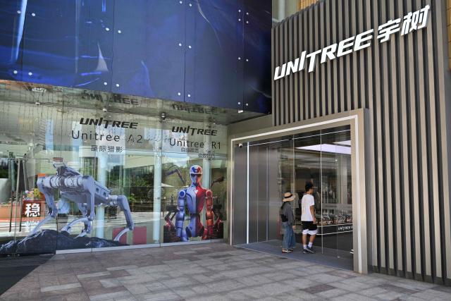 People visit the Unitree Robotics Embodied Intelligence Experience Center in the Jing'an district in Shanghai on August 19, 2026. Shares in Chinese robotics pioneer Unitree soared more than 600 percent on its debut in Shanghai on August 19, after raising more than $900 million in its initial public offering. (Photo by Hector RETAMAL / AFP)