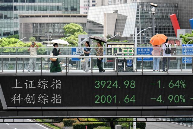 A footbridge with a screen displaying the Shanghai composite index (UP) is seen in the financial district of Shanghai on August 19, 2026. (Photo by Hector RETAMAL / AFP)