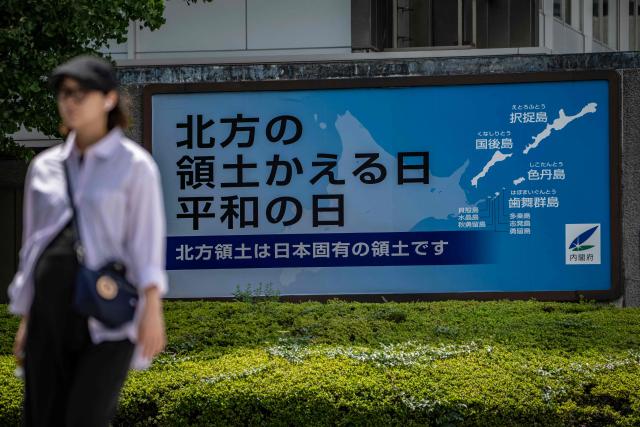 A woman walks past a Japanese government sign reading "Day of the Return of the Northern Territories, Day of Peace. The Northern Territories are an inherent part of Japan's territory,"?referring to the Russian-controlled Southern Kuril Islands claimed by Japan as its Northern Territories, in Tokyo on August 19, 2026. Bilateral relations have long been strained over the Kurils, known in Japan as the Northern Territories. After Russia's President Vladimir Putin visited the islands on August 13, Japan summoned the Russian ambassador in protest, and Russia followed suit. (Photo by Yuichi YAMAZAKI / AFP)