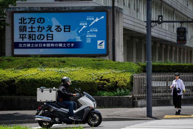 A motorcycle rider passes a Japanese government sign reading "Day of the Return of the Northern Territories, Day of Peace. The Northern Territories are an inherent part of Japan's territory,"?referring to the Russian-controlled Southern Kuril Islands claimed by Japan as its Northern Territories, in Tokyo on August 19, 2026. Bilateral relations have long been strained over the Kurils, known in Japan as the Northern Territories. After Russia's President Vladimir Putin visited the islands on August 13, Japan summoned the Russian ambassador in protest, and Russia followed suit. (Photo by Yuichi YAMAZAKI / AFP)