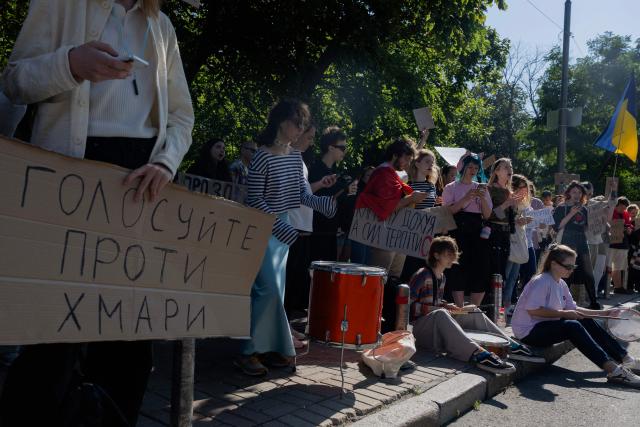 A protester holds a placard (L) reading "Vote against Khmara" during a demonstration before the start of a parliamentary session on the appointment of Ukraine’s new defense minister, in Kyiv on August 19, 2026, amid Russia’s invasion of Ukraine. Ukraine's popular ex-defence minister Mykhailo Fedorov, sacked last month, called on August 18, 2026 for a move towards elections that have been put off because of the Russian invasion. Zelensky has since appointed Yevgeniy Khmara, a career intelligence official with a low political profile, as acting defence minister pending a vote in parliament. (Photo by Tetiana DZHAFAROVA / AFP)