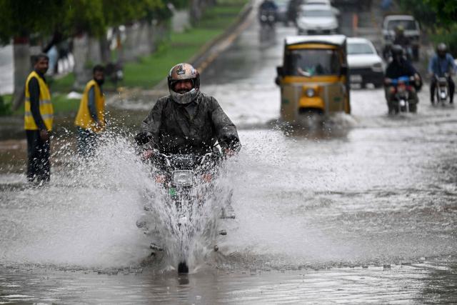 Commuters wade through a flooded street after heavy rainfall in Rawalpindi on August 19, 2026. (Photo by Farooq NAEEM / AFP)