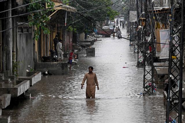 A man wades through a flooded street during rainfall in Rawalpindi on August 19, 2026. (Photo by Farooq NAEEM / AFP)