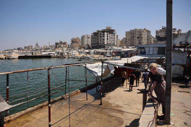 Palestinians stand at a site in Gaza City's port that was targeted by an Israeli army strike the previous day, on August 19, 2026. Gaza health officials said on August 18, 2026, that an Israeli airstrike killed six people in the port of Gaza City and wounded a dozen more, while the Israeli army said it had targeted several Hamas commanders. (Photo by Omar AL-QATTAA / AFP)