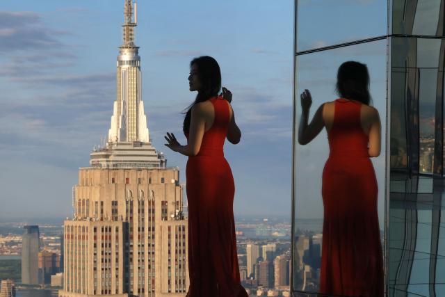 A woman poses for photos as photographers, content creators, and visitors attend an event to celebrate World Photography Day at sunrise at SUMMIT One Vanderbilt in New York City on August 19, 2026. (Photo by TIMOTHY A. CLARY / AFP)