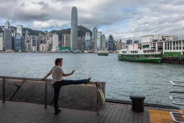An elderly woman exercises next to Victoria harbour and the Star Ferry terminal in Hong Kong on August 19, 2026. (Photo by Dale DE LA REY / AFP)