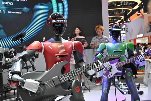 Humanoid robots produced by Casbot play the guitar during the 2026 World Robot conference in Beijing on August 19, 2026. (Photo by ADEK BERRY / AFP)