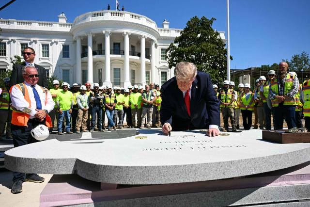 US President Donald Trump signs a piece of stone at the construction site of a helipad on the South Lawn of the White House in Washington, DC, on August 19, 2026. (Photo by Jim WATSON / AFP)