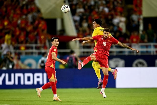 Vietnam's Do Hoang Hen (#10) vies for the ball with Malaysia’s Muhammad Ubaidullah Bin Shamsul Fazili (#3) during the second leg of the 2026 ASEAN Championship football semi-final match between Vietnam and Malaysia at My Dinh National Stadium in Hanoi on August 19, 2026. (Photo by Nhac NGUYEN / AFP)