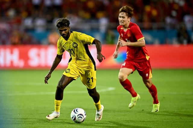 Vietnam's Nguyen Hoang Duc (#14) vies for the ball with Malaysia’s Pavithran Gunalan (#21) during the second leg of the 2026 ASEAN Championship football semi-final match between Vietnam and Malaysia at My Dinh National Stadium in Hanoi on August 19, 2026. (Photo by Nhac NGUYEN / AFP)