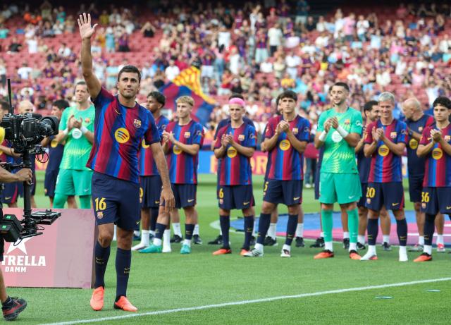 Barcelona's new player, Spanish international Rodrigo Hernandez "Rodri" (L) gestures to supporters during the 61st Joan Gamper Trophy football match between FC Barcelona and Al Ahly FC at the Camp Nou Stadium in Barcelona on August 19, 2026. (Photo by Lluis GENE / AFP)