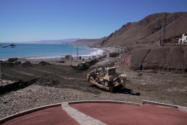 This image shows heavy machinery working at the Coloso fishermen's cove, affected by a mudslide following heavy rainfall in Antofagasta, northern Chile, on August 19, 2026. (Photo by SEBASTIAN ROJAS ROJO / AFP)