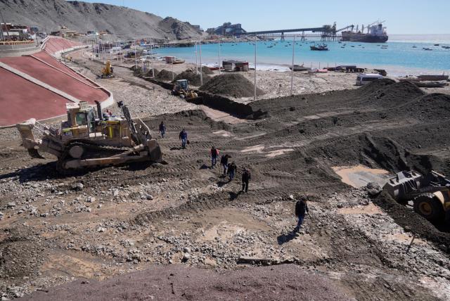 This image shows heavy machinery working at the Coloso fishermen's cove, affected by a mudslide following heavy rainfall in Antofagasta, northern Chile, on August 19, 2026. (Photo by SEBASTIAN ROJAS ROJO / AFP)