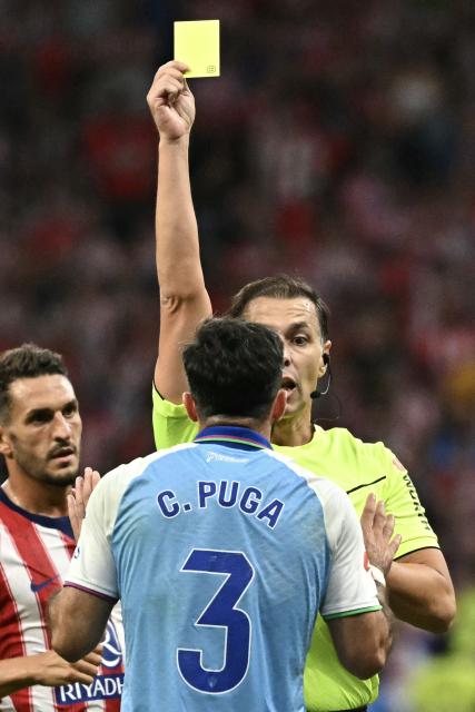 Malaga's Spanish defender #03 Carlos Puga receives a yellow card during the Spanish league football match between Club Atletico de Madrid and Malaga CF at the Metropolitano Stadium in Madrid on August 19, 2026. (Photo by Javier SORIANO / AFP)