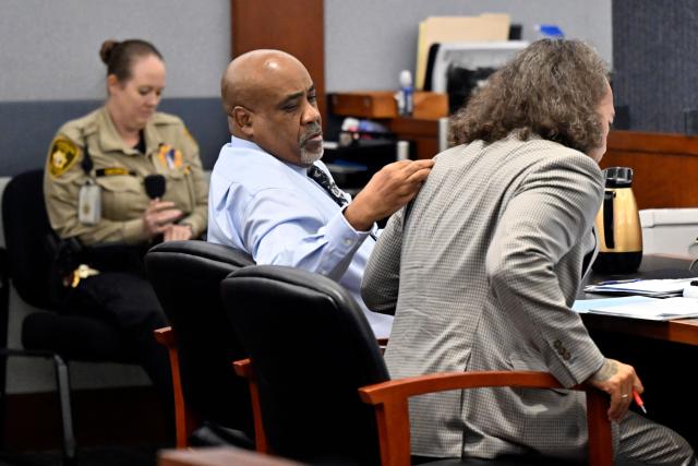 Duane Davis (L) removes a piece of lint from his defense attorney Michael Sanft's jacket during his murder trial, related to the 1996 killing of rapper Tupac Shakur, at Clark County District Court at the Regional Justice Center in Las Vegas, Nevada, on August 19, 2026. The trial of the former gang leader accused of orchestrating the murder of rapper Tupac Shakur began on August 10, 30 years after one of America's most high-profile unresolved killings. The proceedings, expected to last a month, will likely not make clear who fired the shots that killed the California hip-hop legend on the night of September 7, 1996, while he was in Las Vegas to see a Mike Tyson boxing match. (Photo by David Becker / POOL / AFP)