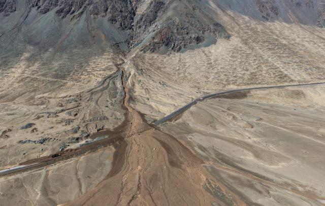 This aerial view shows a highway covered with mud and debris after a landslide struck the city of Iquique, due to heavy rainfall in the north of Chile on August 19, 2026. (Photo by Alex DIAZ / AFP)
