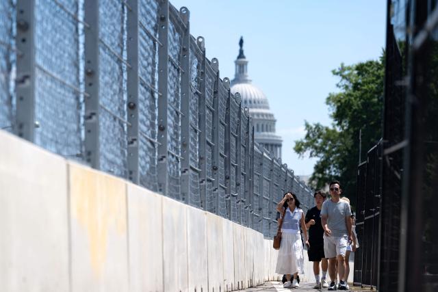 People walk along the track fencing in Washington, DC, on August 19, 2026, ahead of the Freedom 250 Grand Prix. The Freedom 250 Grand Prix will take place on a temporary 1.7-mile, seven-turn street circuit around the National Mall, with practice and qualifying on Saturday before the main NTT IndyCar Series race on Sunday, August 23. (Photo by Kent Nishimura / AFP)