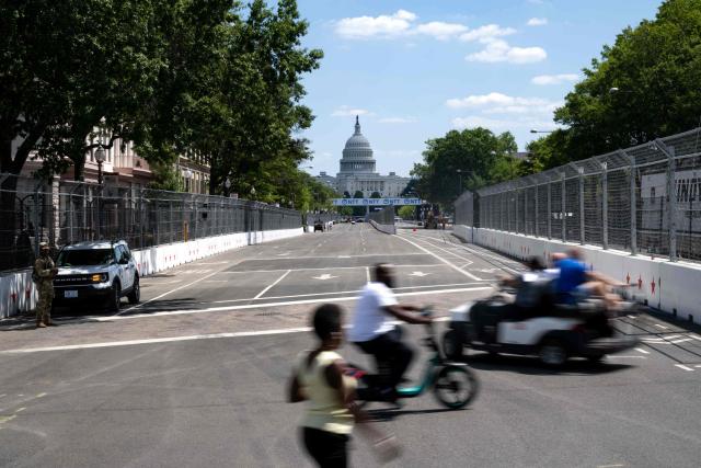 People cross the temporary race track along Pennsylvania Avenue in Washington, DC, on August 19, 2026, ahead of the Freedom 250 Grand Prix. The Freedom 250 Grand Prix will take place on a temporary 1.7-mile, seven-turn street circuit around the National Mall, with practice and qualifying on Saturday before the main NTT IndyCar Series race on Sunday, August 23. (Photo by Kent Nishimura / AFP)