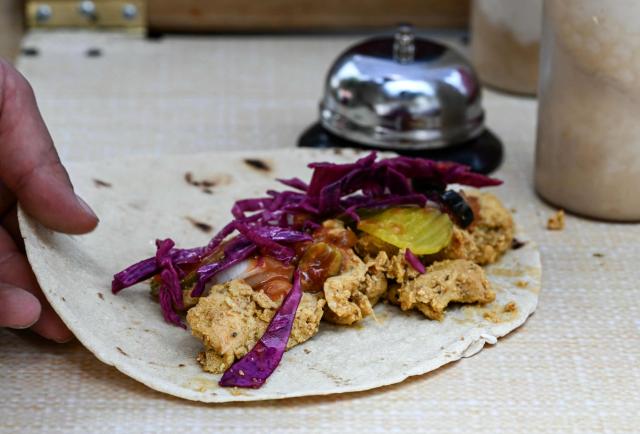 Palestinian Fadi Abed prepares chicken shawarma at his food stall "Hijo de Palestina", in La Plaza del Bolero in Tlalpan, on the outskirts of Mexico City, on August 14, 2026. Abed —one of 18 members of the Abed family, the first refugees to arrive in Mexico following Israeli bombardments of the Gaza Strip— launched a Palestinian food business which went viral and became highly popular thanks to the "Cumbia del Falafel"—a promotional jingle he plays as he drives his tricycle through the streets of Tlalpan and Mexico City. (Photo by Yuri CORTEZ / AFP)
