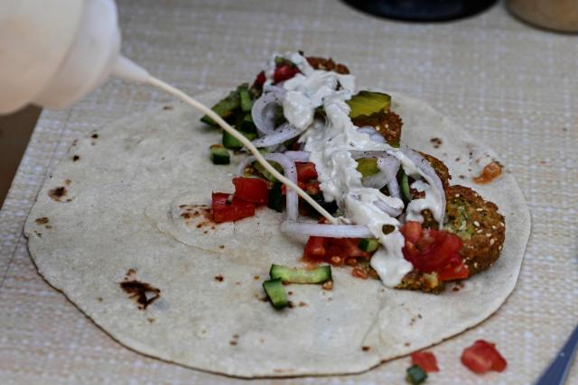 Palestinian Fadi Abed prepares falafel shawarma at his food stall "Hijo de Palestina", in La Plaza del Bolero in Tlalpan, on the outskirts of Mexico City, on August 14, 2026. Abed —one of 18 members of the Abed family, the first refugees to arrive in Mexico following Israeli bombardments of the Gaza Strip— launched a Palestinian food business which went viral and became highly popular thanks to the "Cumbia del Falafel"—a promotional jingle he plays as he drives his tricycle through the streets of Tlalpan and Mexico City. (Photo by Yuri CORTEZ / AFP)