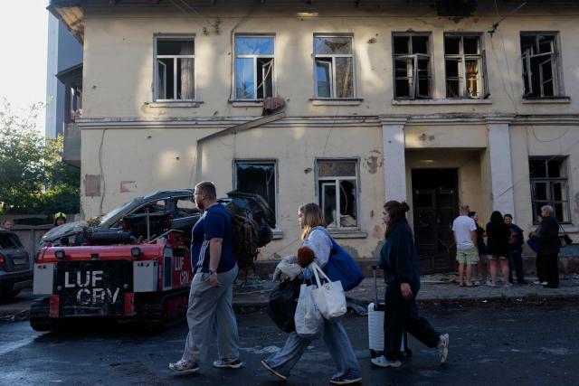 People walk past a damaged residential building following a Russian strike in Kyiv on August 20, 2026, amid Russia’s invasion of Ukraine. Russian bombardment killed six people and wounded dozens in Ukraine's capital and its surrounding region overnight, authorities said on August 20. (Photo by Tetiana DZHAFAROVA / AFP)
