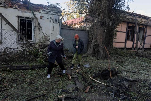 Women look at a hole in the asphalt following a Russian strike in Kyiv on August 20, 2026, amid Russia’s invasion of Ukraine. Russian bombardment killed six people and wounded dozens in Ukraine's capital and its surrounding region overnight, authorities said on August 20. (Photo by Tetiana DZHAFAROVA / AFP)