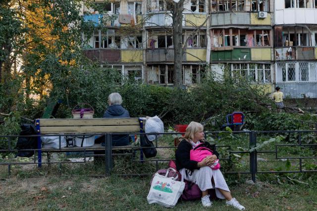 A woman sits near a damaged residential building following a Russian strike  in Kyiv on August 20, 2026, amid Russia’s invasion of Ukraine. Russian bombardment killed six people and wounded dozens in Ukraine's capital and its surrounding region overnight, authorities said on August 20. (Photo by Tetiana DZHAFAROVA / AFP)