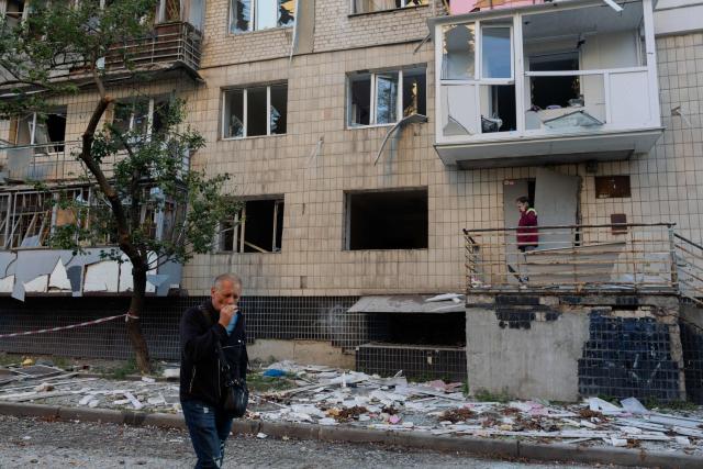 A man smokes as he walks near a damaged residential building following a Russian strike in Kyiv on August 20, 2026, amid Russia’s invasion of Ukraine. Russian bombardment killed six people and wounded dozens in Ukraine's capital and its surrounding region overnight, authorities said on August 20. (Photo by Tetiana DZHAFAROVA / AFP)