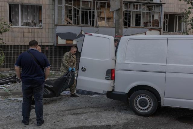 A victim's body is placed into a minivan next to a damaged residential building following a Russian strike in Kyiv that also hit a nearby hospital, on August 20, 2026, amid Russia's invasion of Ukraine. Russian bombardments killed at least 12 people and wounded dozens in Ukraine's capital and its surrounding region overnight, authorities said on August 20. (Photo by Roman PILIPEY / AFP)