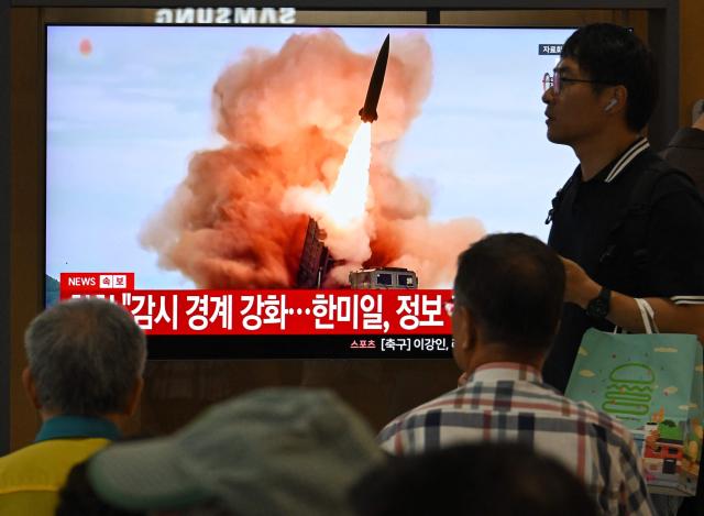 People watch a television screen showing a news broadcast with file footage of a North Korean missile test, at a train station in Seoul on August 20, 2026. North Korea fired around 10 short-range ballistic missiles, South Korea's military said on August 20, hours after US President Donald Trump said he would meet Pyongyang's leader Kim Jong Un later this year. (Photo by Jung Yeon-je / AFP)